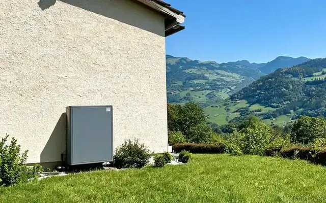 Pompe à chaleur air-eau installée contre la façade d'une maison de Bulle, dans la Gruyère fribourgeoise