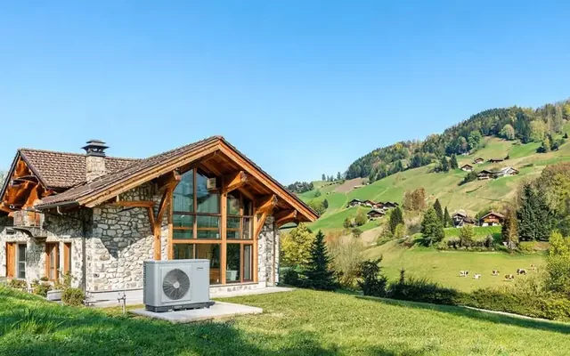 Installation extérieure d'une pompe à chaleur air-eau moderne devant une villa du canton de Fribourg